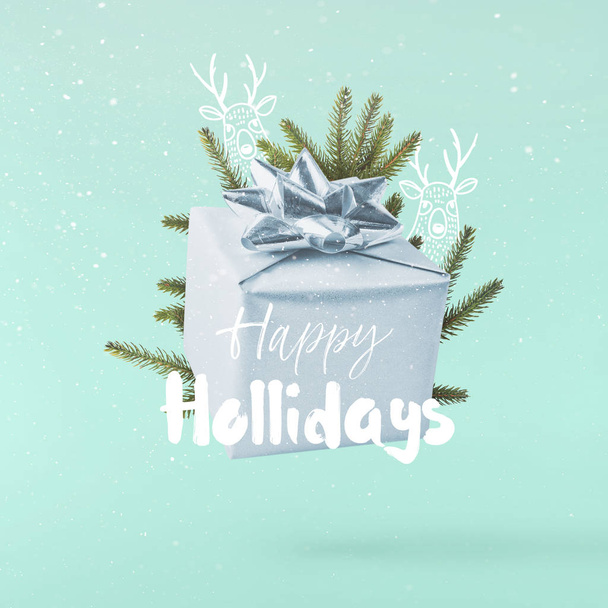 Kerst concept. Creatieve Kerstmis conception gemaakt door omvallen turkooizen achtergrond in lucht zilveren geschenkbox. Minimale concept - Foto, afbeelding