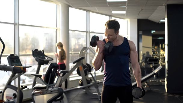workout in gym, muscular bodybuilder lifting weight, doing dumbbell curls - Fotografie, Obrázek