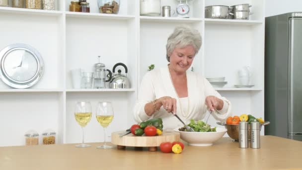 Happy senior couple preparing a salad in the kitchen - Footage, Video