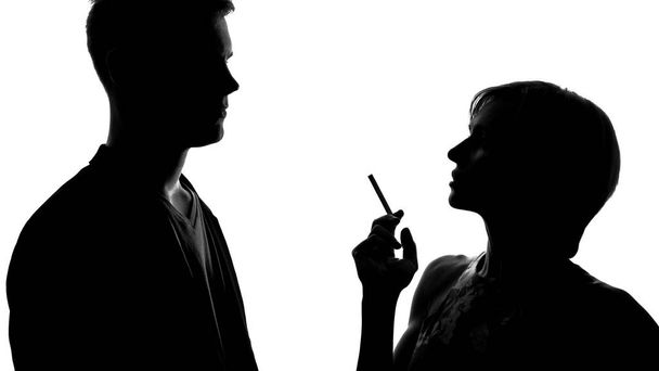 Silhouette of young female holding cigarette and flirting with man, party - Foto, afbeelding
