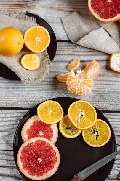Delicious various types of citrus fruit in plates on wooden background - Фото, изображение
