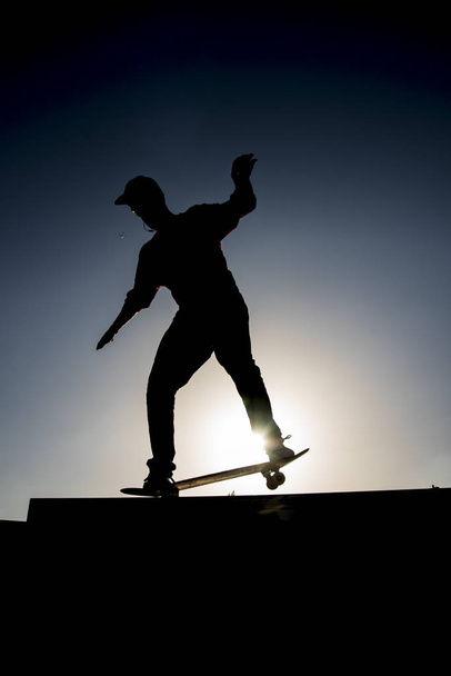 Silhouette of a Skater riding the skate in a half pipe in a skate park in lisbon - Photo, Image