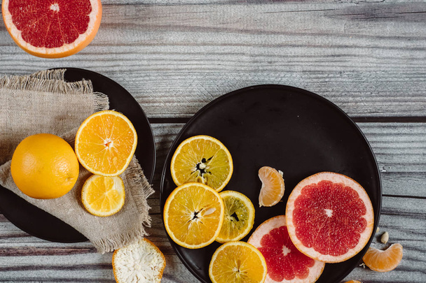 Delicious various types of citrus fruit in plates on wooden background - Foto, Imagem