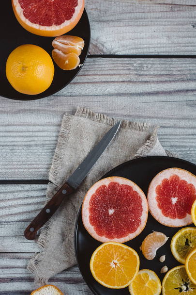 Delicious various types of citrus fruit in plates on wooden background - Foto, afbeelding