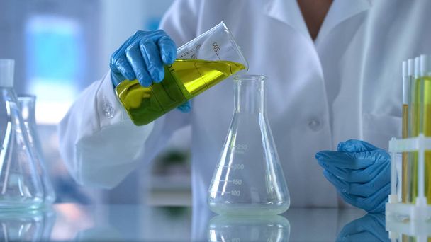 Researcher pouring yellow substance in test tube, oil quality, new petrol - Fotó, kép
