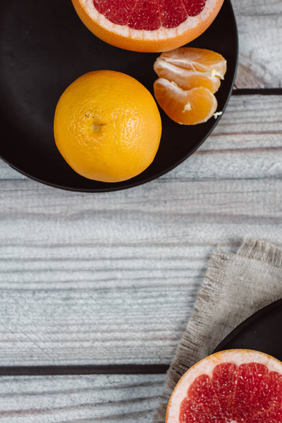 Delicious various types of citrus fruit in plates on wooden background - 写真・画像
