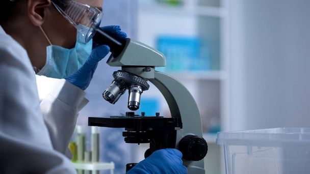 Lab technician examining test sample through microscope new medicine development - Photo, image