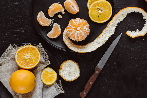 Delicious various types fresh cut of citrus fruit in plates on dark background - Foto, afbeelding