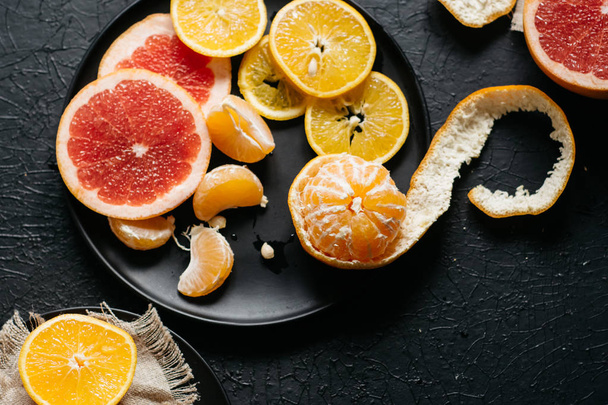 Delicious various types fresh of citrus fruit in plates on dark background - Foto, Imagem