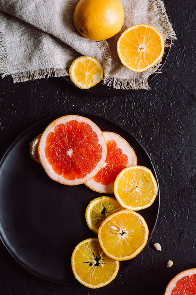 Delicious various types fresh of citrus fruit in plates on dark background - Foto, afbeelding