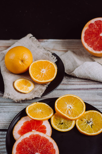 Delicious various types of citrus fruit in plates on wooden background - Foto, Imagem