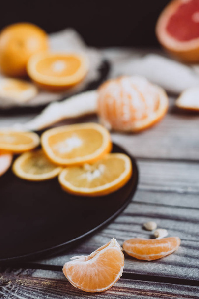 Delicious various types of citrus fruit in plates on wooden background - Foto, afbeelding