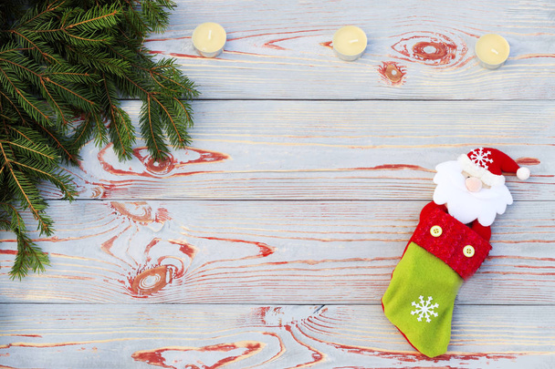 Різдвяний шкарпетка на дерев'яному фоні. Іграшковий та різдвяний панчохи, є гілка ялиці. Різдвяні та новорічні прикраси. Святкова концепція свята
. - Фото, зображення