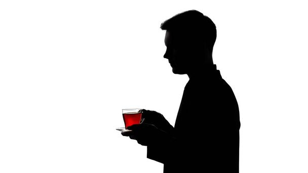 Dark silhouette of man drinking glass of tea, recreation, pH balance restore - Foto, Bild