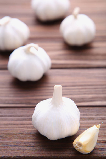 Fresh garlic on a brown background. Garlic on brown wooden table - Фото, зображення