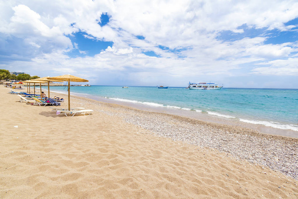 Παραλία Στεγνά με ομπρέλες, ξαπλώστρες και βάρκες στο παρασκήνιο (Ρόδος, Ελλάδα) - Φωτογραφία, εικόνα