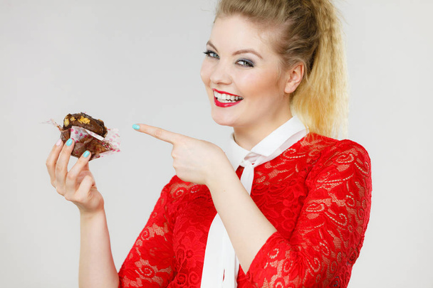 Sweet food sugar make us happy. Attractive blonde woman holds yummy chocolate cupcake in hand, open mouth, craving for cake. - Foto, Imagen