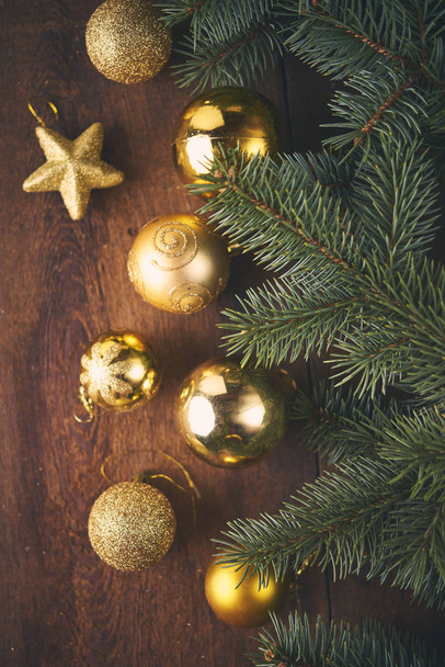 Weihnachtlicher Hintergrund. jede Menge Goldkugeln und Tannenbäume über dunklem Holzbrett. Weihnachtskonzept - Foto, Bild