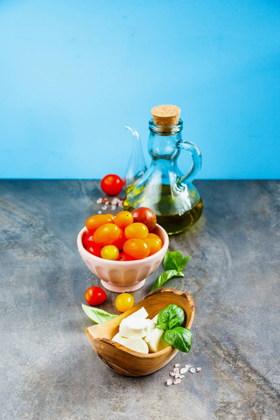 Моцарелла оливковое масло листья томатного базилика на синем фоне. Итальянский салат. Средиземноморский салат. Итальянская кухня. Средиземноморская кухня
. - Фото, изображение