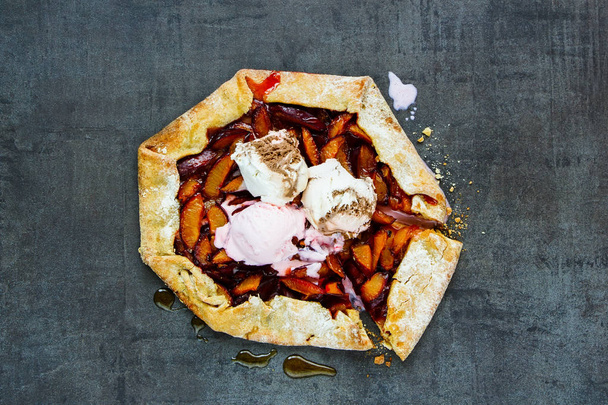 Plum pie or tart with ice cream close up. Seasonal Fall or Autumn dessert. Flat lay - 写真・画像