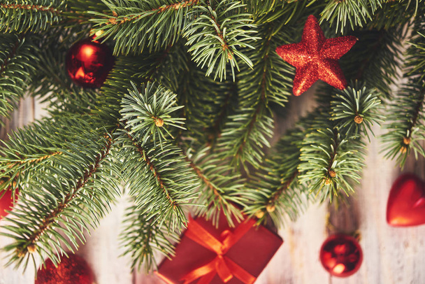 Kerstmis achtergrond. Fir tree and alot of rode kerstballen en de doos van de gift over witte houten plank - Foto, afbeelding