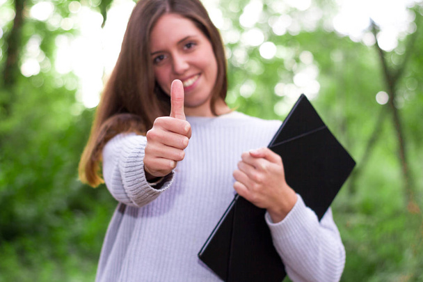 Mulher ou jovem caucasiana universitária europeia ou estudante com gesto afirmativo polegares para cima segurando uma pasta depois de aulas de Inglês
 - Foto, Imagem