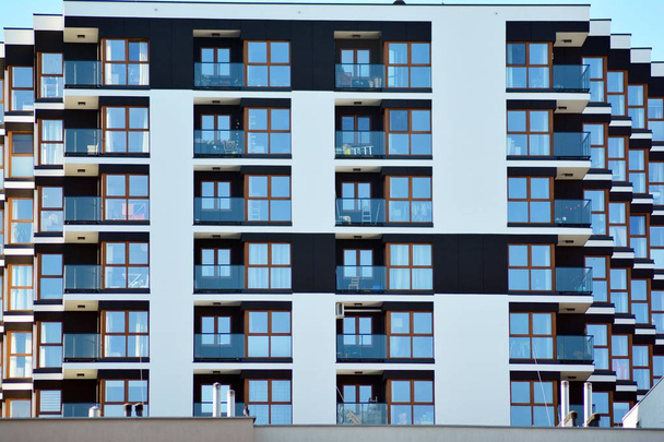Fragment van een gevel van een gebouw met ramen en balkons. Moderne woning met veel appartementen. - Foto, afbeelding