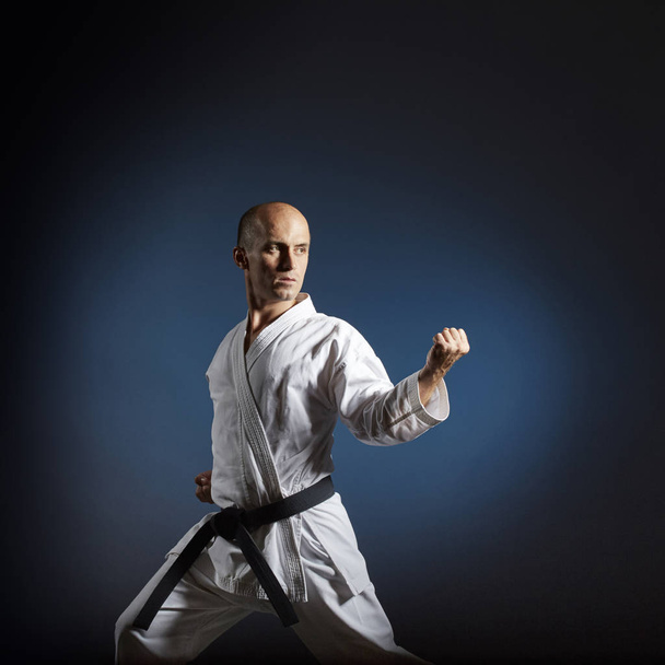 Sportowiec trenuje karate formalne ćwiczenia na niebieskim tle z gradientem - Zdjęcie, obraz