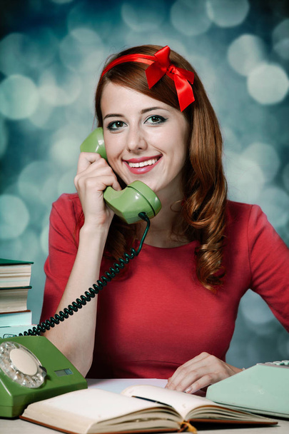 Młoda kobieta jako sekretarz przy biurku w pobliżu maszyny do pisania i wybierania numeru telefonu. styl 60-s. - Zdjęcie, obraz