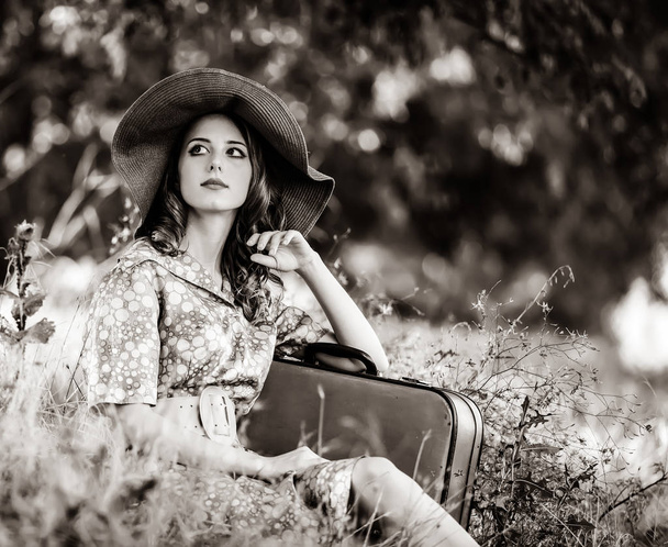 girl with suitcase sitting at autumn grass - Fotoğraf, Görsel
