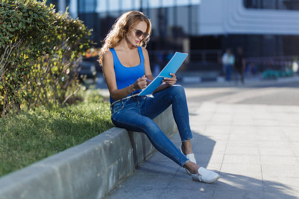 beautiful young woman holding a notebook in her hands on the street. concept of business or education lifestyle - Foto, Bild
