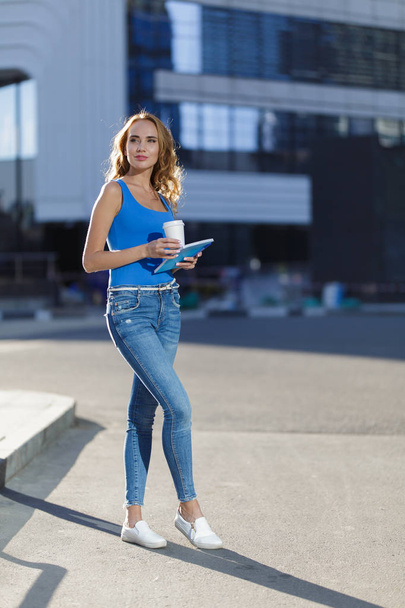 Beautiful young woman holding notebook and cup of coffe standing on the street. concept of business or education lifestyle - Photo, image