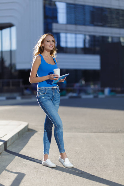 Beautiful young woman holding notebook and cup of coffe standing on the street. concept of business or education lifestyle - Foto, immagini