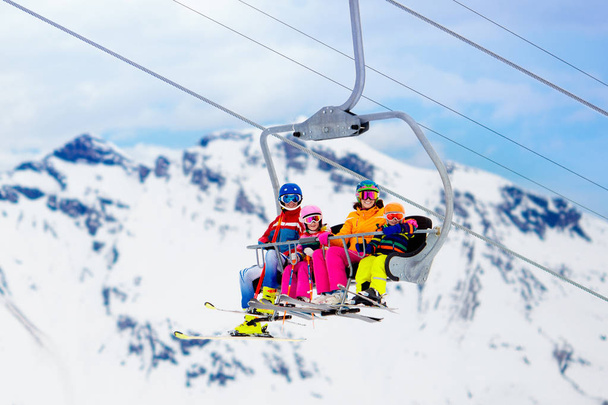 Familie in de skilift in de bergen van de Zwitserse Alpen. Skiën met jonge kinderen. Vader, moeder en kinderen zitten in de skilift tijdens de kerstvakantie. Winter outdoor sporten voor actieve familie.  - Foto, afbeelding