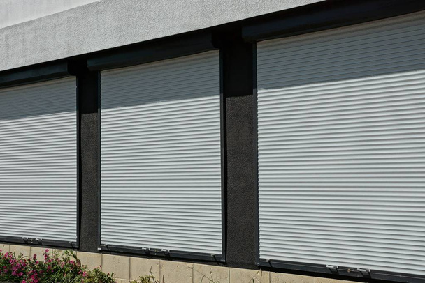 három windows borított fehér műanyag redőnyök, a ház falán - Fotó, kép