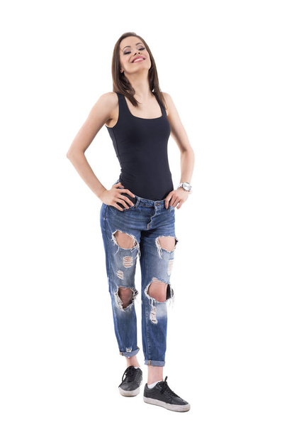 Confident lovely young woman in torn ripped jeans posing in akimbo posture. Full body isolated on white background.  - Foto, imagen