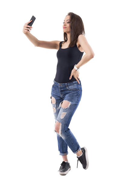 Confident sexy young adult passionate woman taking selfie photos with mobile phone. Full body isolated on white background.  - Фото, изображение