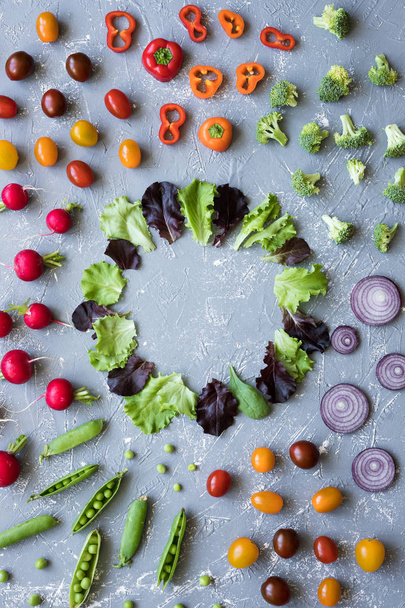 Marco de verduras orgánicas frescas. Rábano, guisantes verdes, brócoli, tomate y cebolla sobre fondo gris, con espacio para copiar
. - Foto, Imagen