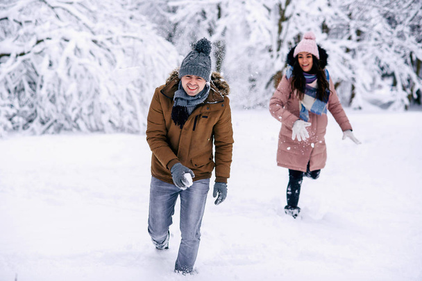 Kochający Młoda para bawi się śnieżkami w winter park. Koncept rodziny miłości i opieki. - Zdjęcie, obraz