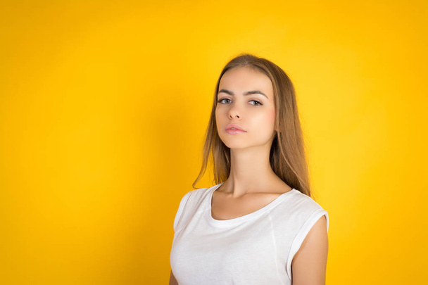 portrait of a beautiful young girl in a white shirt on a yellow background - Foto, immagini