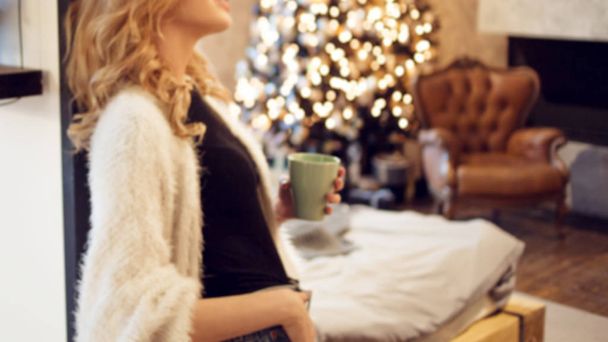 Morning of new day and new year. Young happy woman at home. Bedroom interior with Christmas tree - Photo, Image