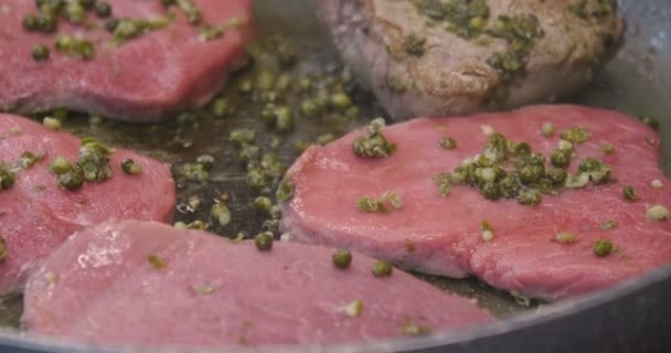 A chef, in a professional kitchen, cooks a tender tenderloin of meat in a professional pan. Concept of: cooking, chef, gourmet, italian food - Filmagem, Vídeo