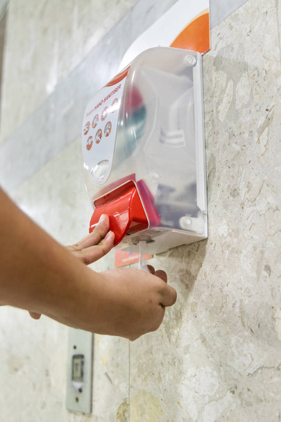 Person dispensing disinfectant sanitizer liquid onto hand at public amenities or hygienic living - Photo, Image