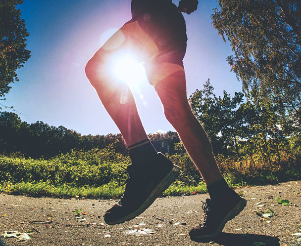 Urheilija harjoittelemassa puistossa. Mies juoksee tai hyppii, venyttelee ruumistaan. Hyvä terveyskäsite
 - Valokuva, kuva