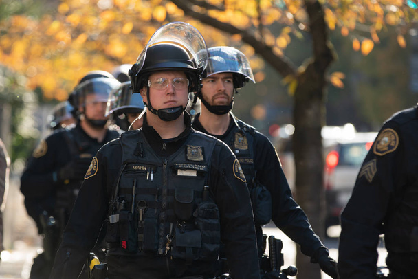 Portland, lub / Usa - 17 listopada 2018 r.: Grupa oficerów policji w riot gear, idąc ulicą podczas protestu Antifa w centrum. - Zdjęcie, obraz