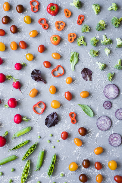 Clean eating concept. Fresh organic vegetables. Radish, green peas, broccoli, tomato and onion on grey background.  - Фото, зображення