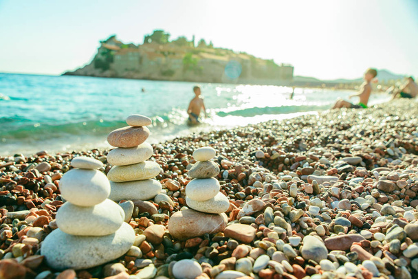 rocas equilibradas a orillas del mar. playa rocosa al atardecer. niños nadando en el fondo. vacaciones en montenegro
 - Foto, Imagen