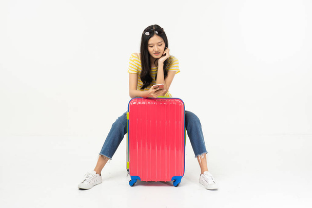 Beautiful young woman smiling and pulling pink color luggage isolated on white background.Woman going to summer vacation.Travel trip funny. - Фото, изображение