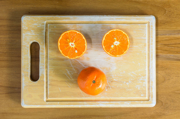 A sliced orange by knife on the wood block and on the wood table. - Foto, Imagen