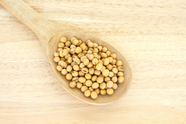 soy bean zaad in lepel gezonde plantaardige voeding op houten achtergrond - Foto, afbeelding